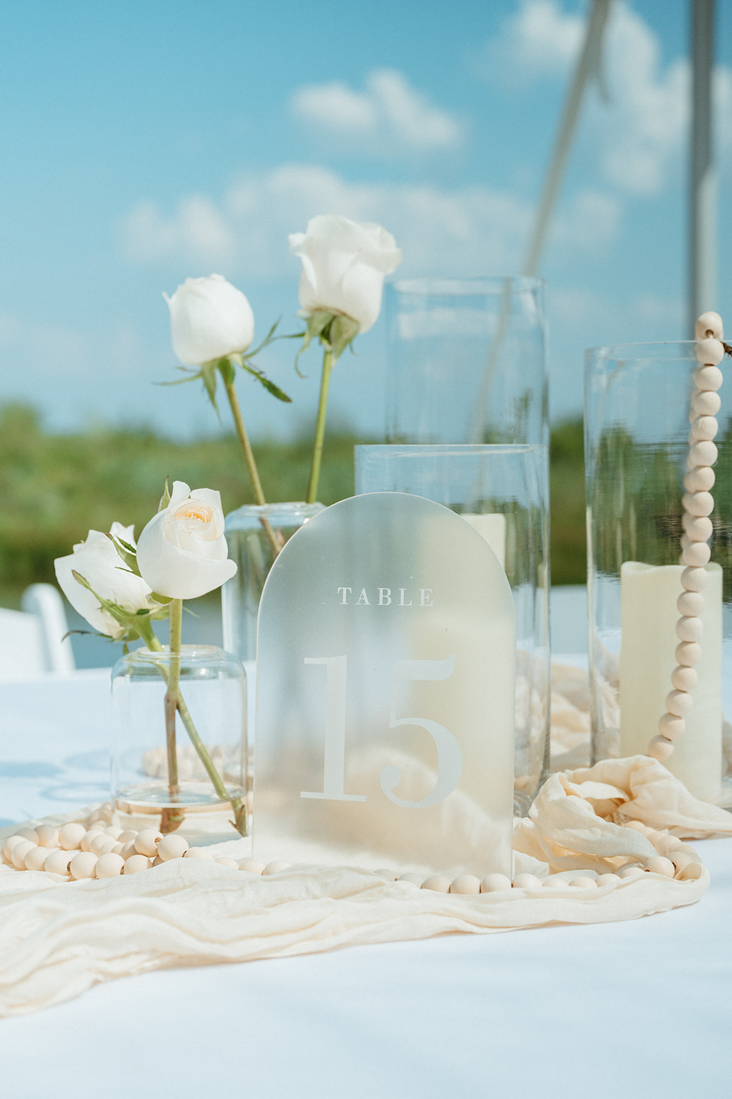 A reception table set with white roses and candles, Lake Huron glittering behind it