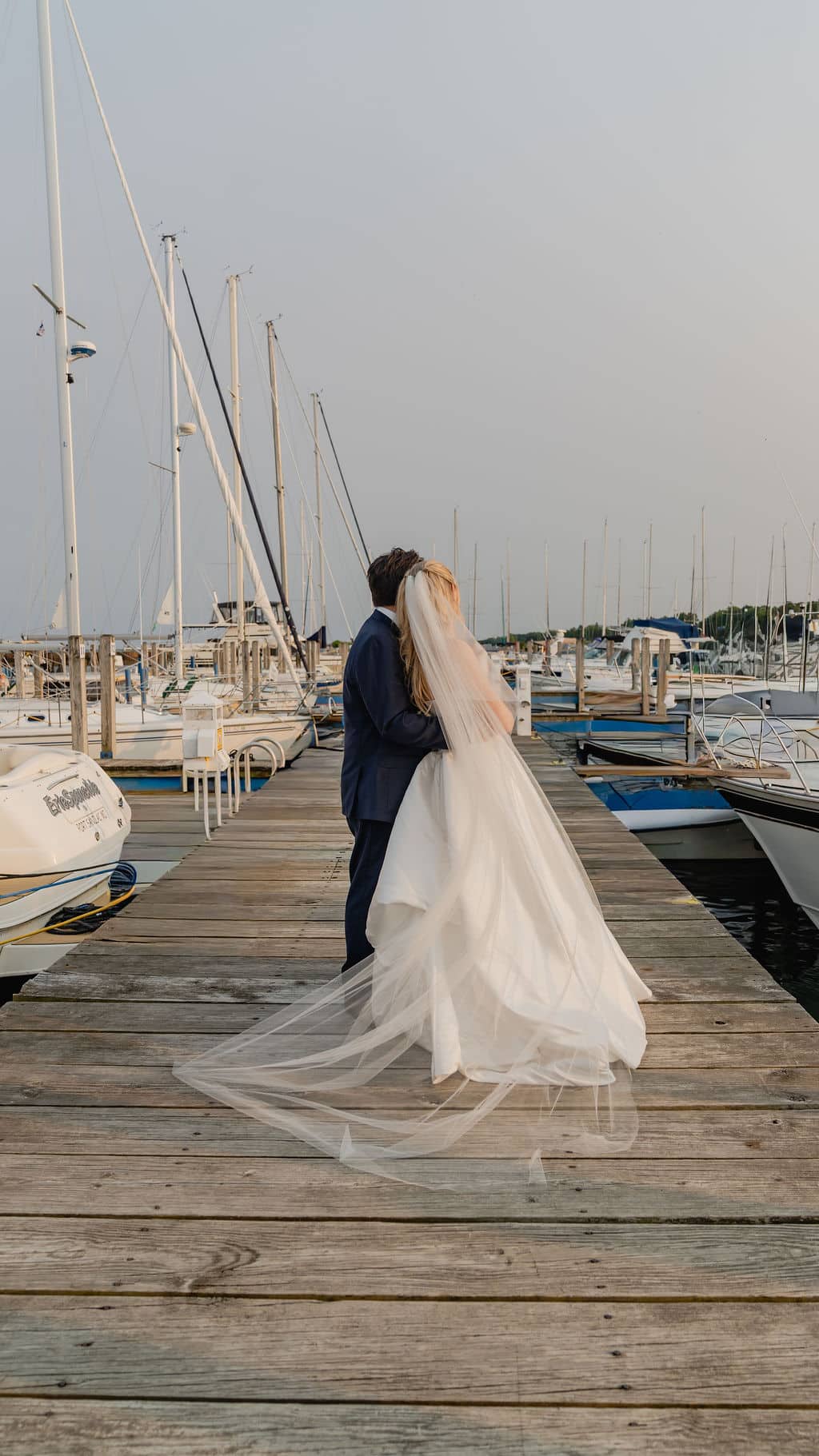 A bride and groom walking together down a dock at the harbor