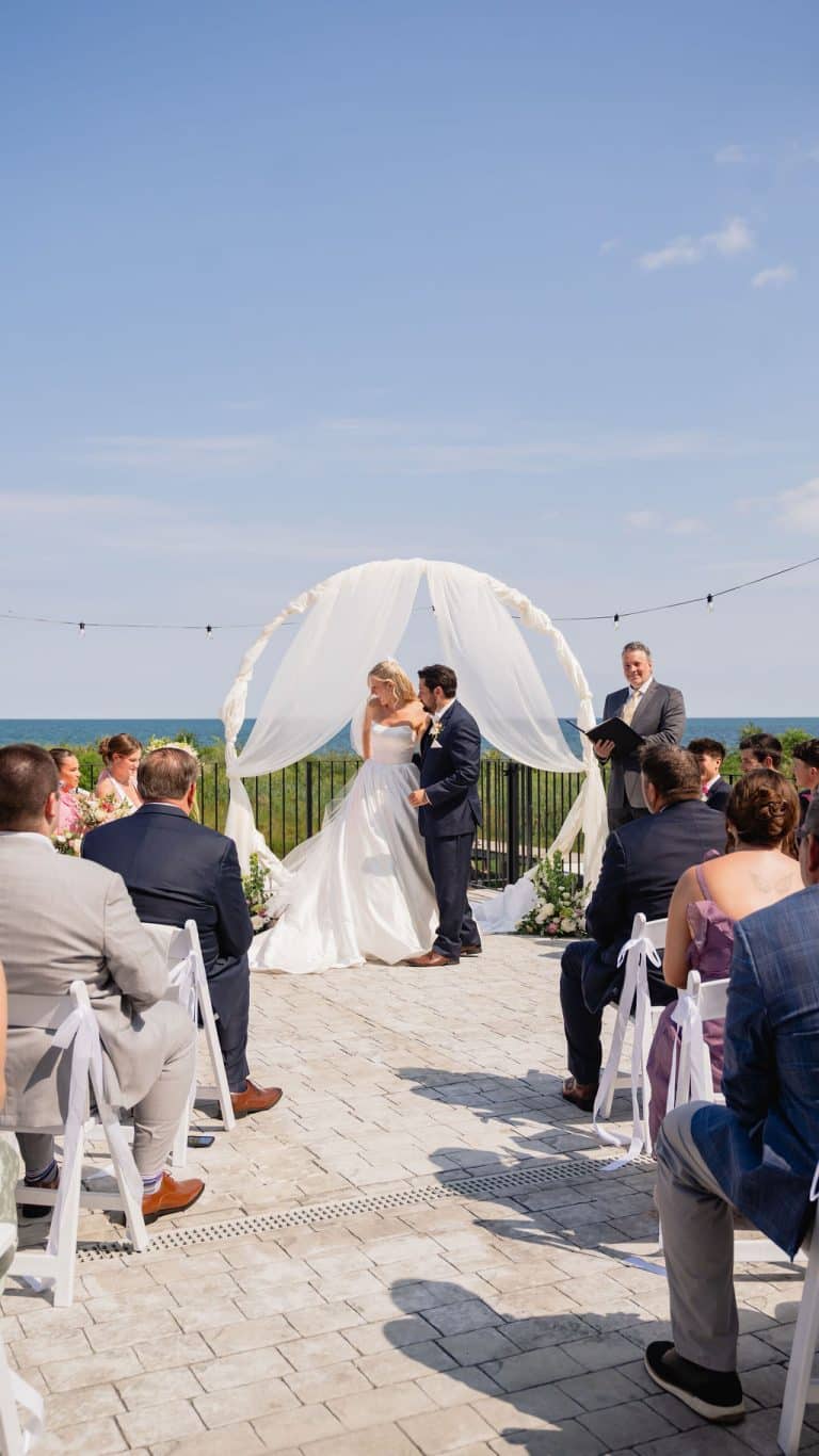 A ceremony beneath a draped arch with the lake behind the couple