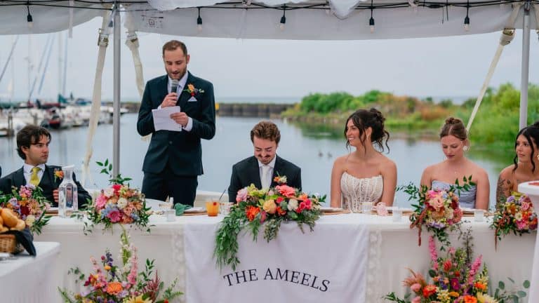 The sweetheart table during toasts, with the lake beyond