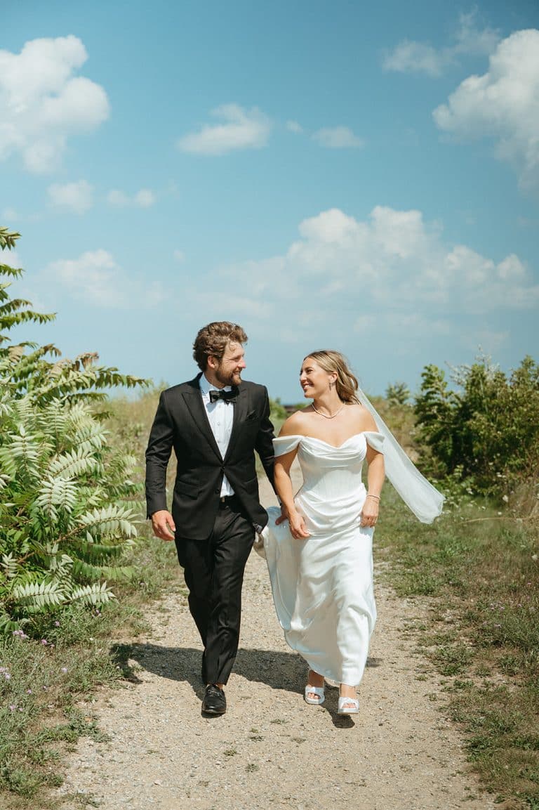 Newlyweds walking hand in hand along a lakeside path