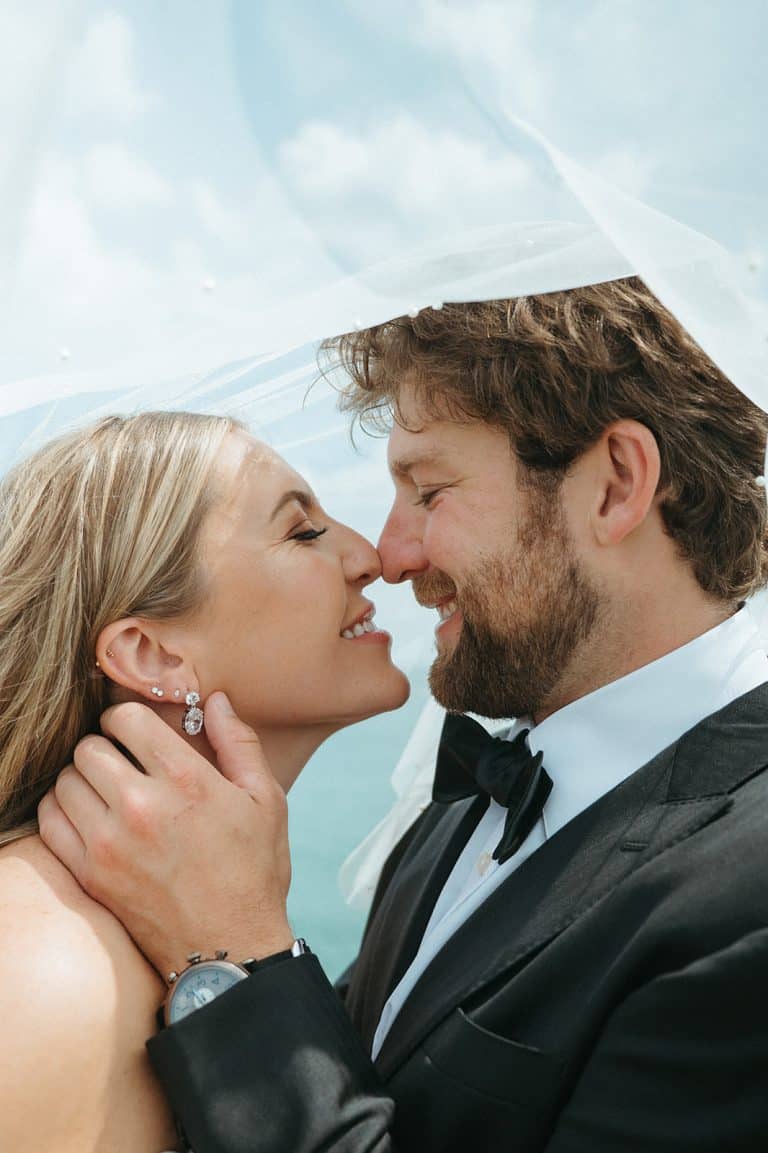 A bride and groom nose to nose, smiling