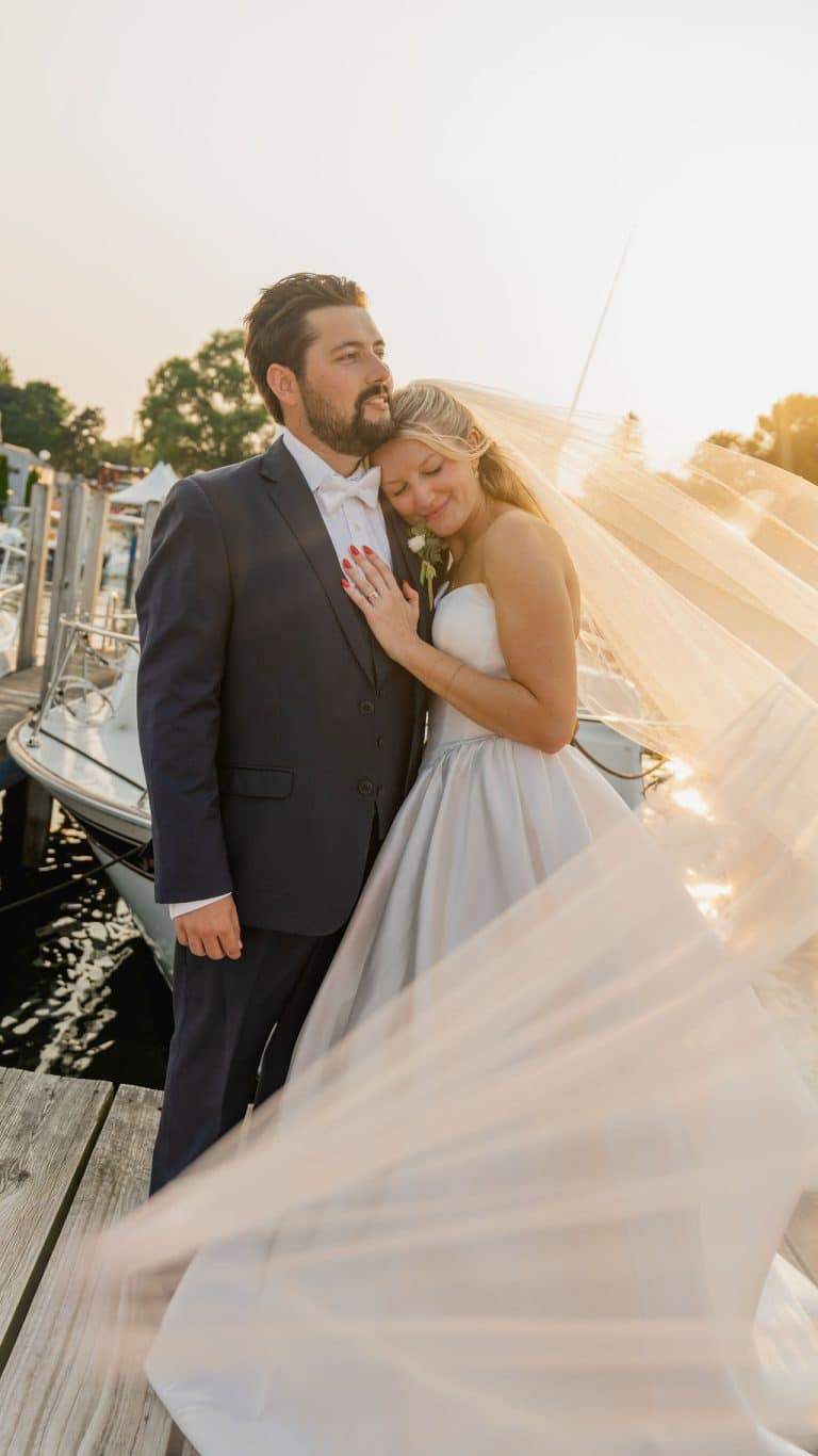 A groom holding his bride close at the harbor